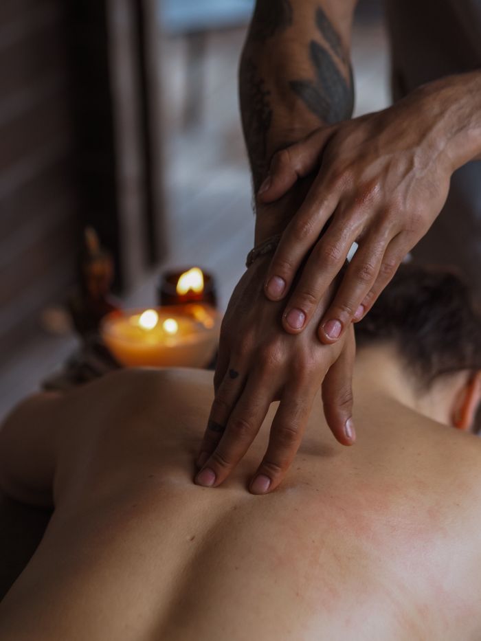 Close-up of a soothing back massage in a candlelit spa, promoting relaxation and wellness.